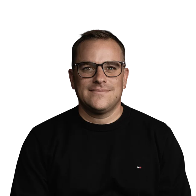 Porträt eines lächelnden Mannes mit schwarzen Brillengläsern und schwarzem Hemd