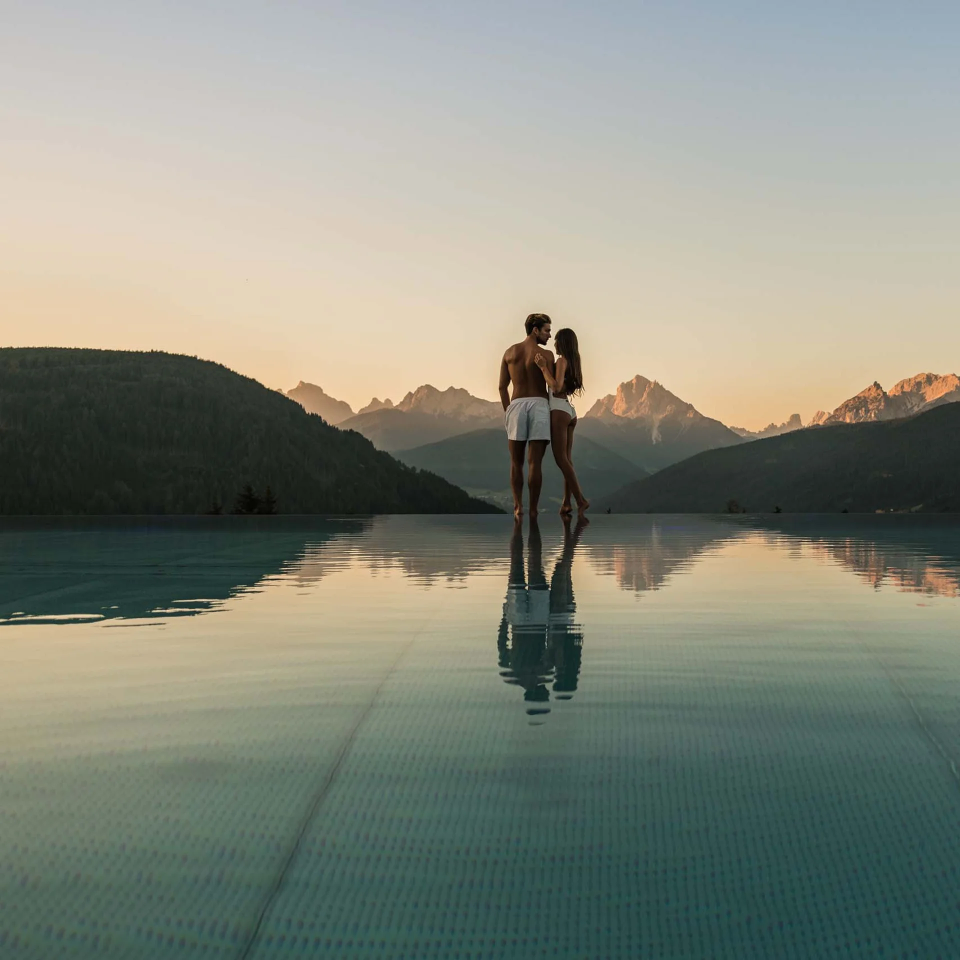 A stylish new website for the Alpen Tesitin in South Tyrol Couple in infinity pool overlooking mountains at sunset