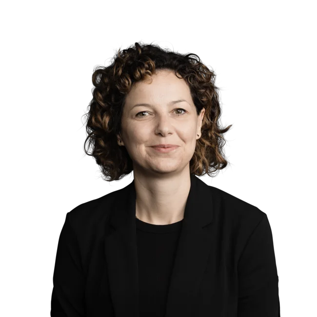 Porträt einer lächelnden Frau mit lockigem Haar in schwarzem Blazer