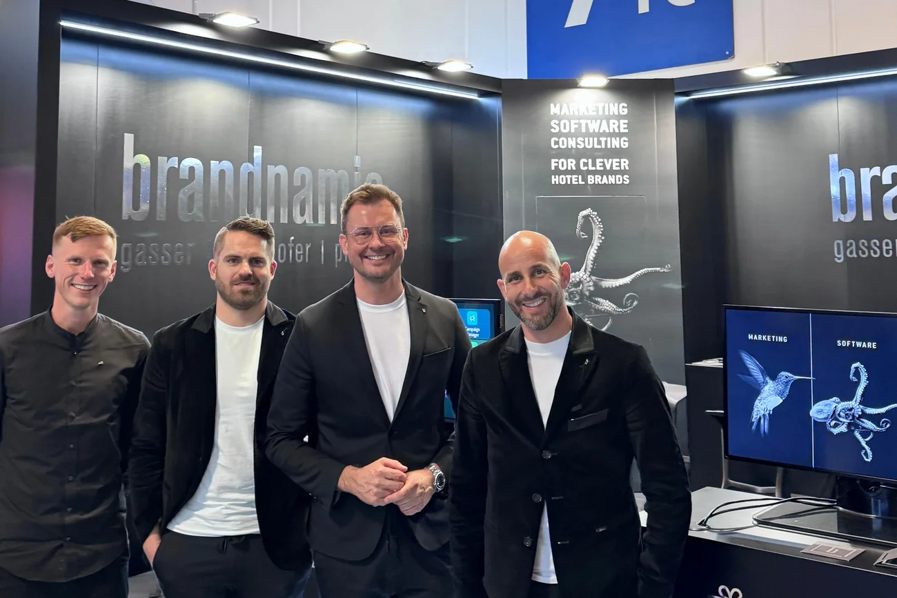 Vier Männer stehen vor Messestand mit Marketing- und Softwareanzeigen