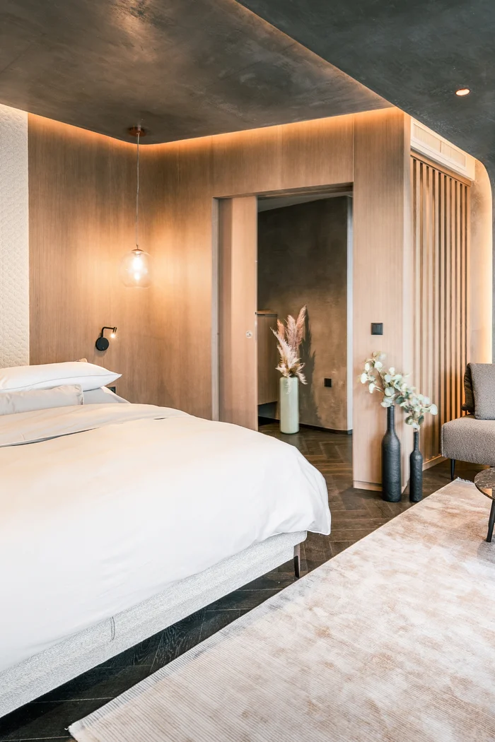 Modernes Schlafzimmer mit Holzpaneelen, Bett und Sitzecke