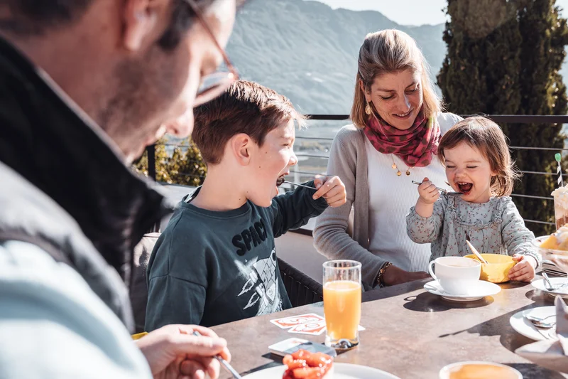 Die Familienhotels Südtirol – branded by Brandnamic Familie isst zusammen draußen mit Bergen im Hintergrund