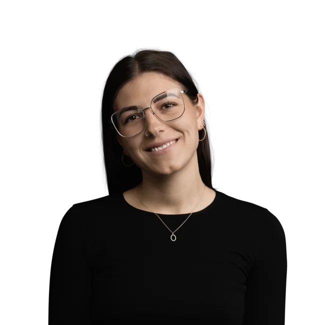 Junge Frau mit Brille, schwarzem Oberteil und dezentem Schmuck lächelt