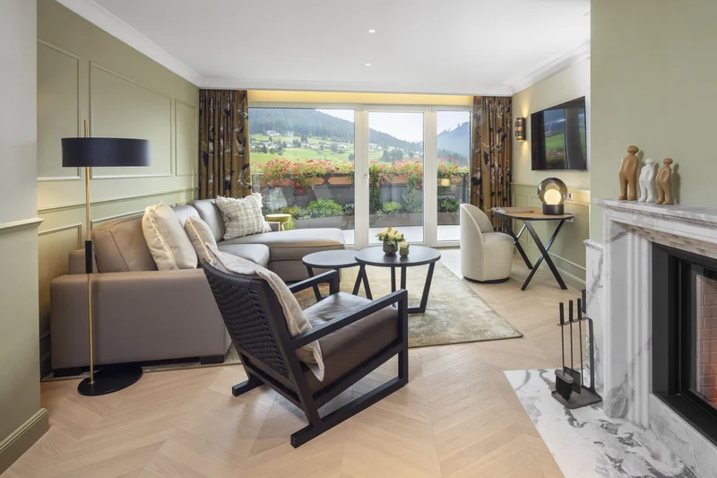 Modernes Wohnzimmer mit Kamin, Sofa, Sessel und Blick auf Berglandschaft