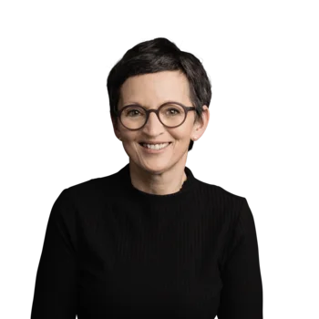 Frau mit kurzen dunklen Haaren, runder Brille und schwarzem Pullover lächelnd
