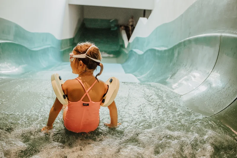 Das Mühlwald: perfectly visible Child in pink swimsuit sliding down a water slide wearing floaties