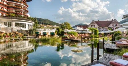 Die besten Referenzen für unser Hotelmarketing Hotel mit Teich, Liegestühlen und Sonnenschirmen bei sonnigem Wetter