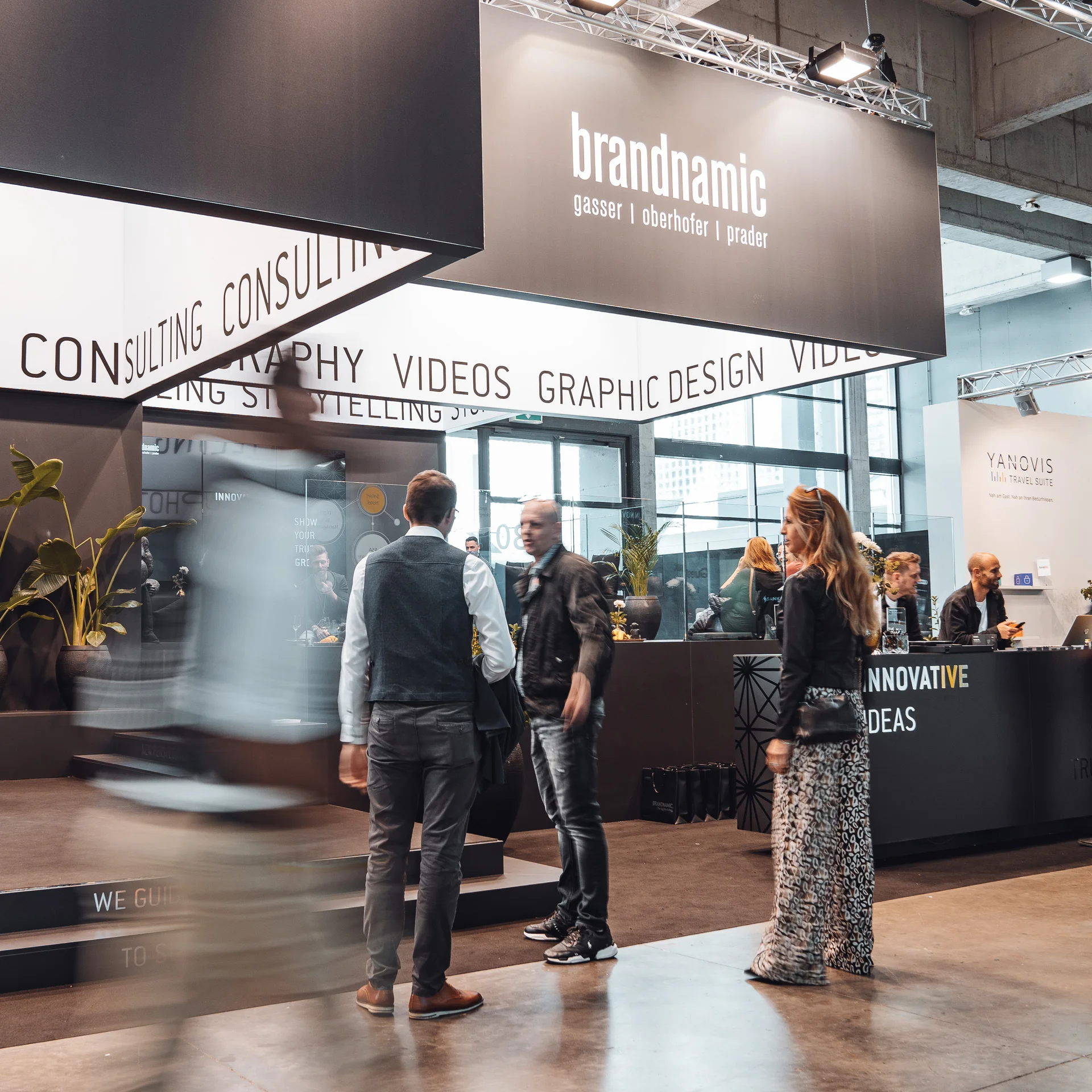 Menschen auf einer Messe vor einem Stand mit Meet & Greet Tafel