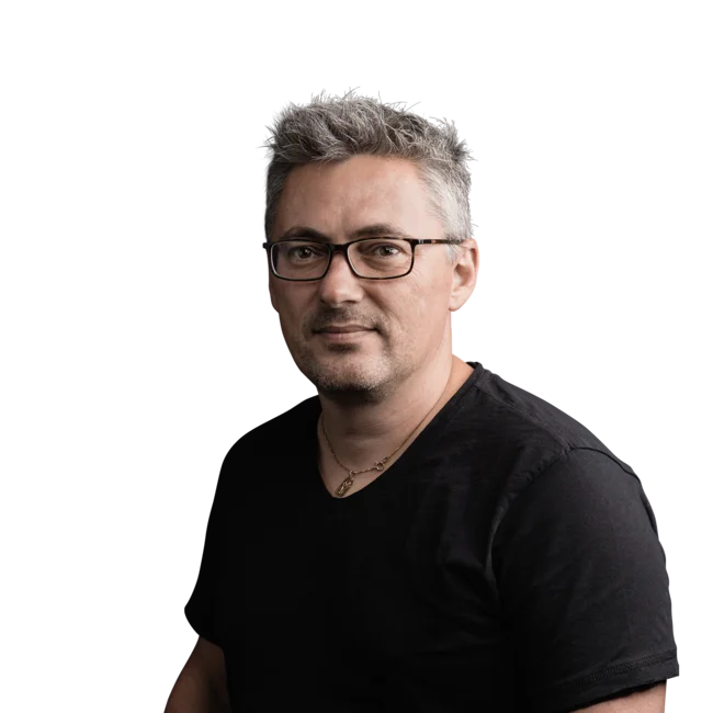 Julian Stricker Porträt eines Mannes mit Brille und grau meliertem Haar in schwarzem T-Shirt
