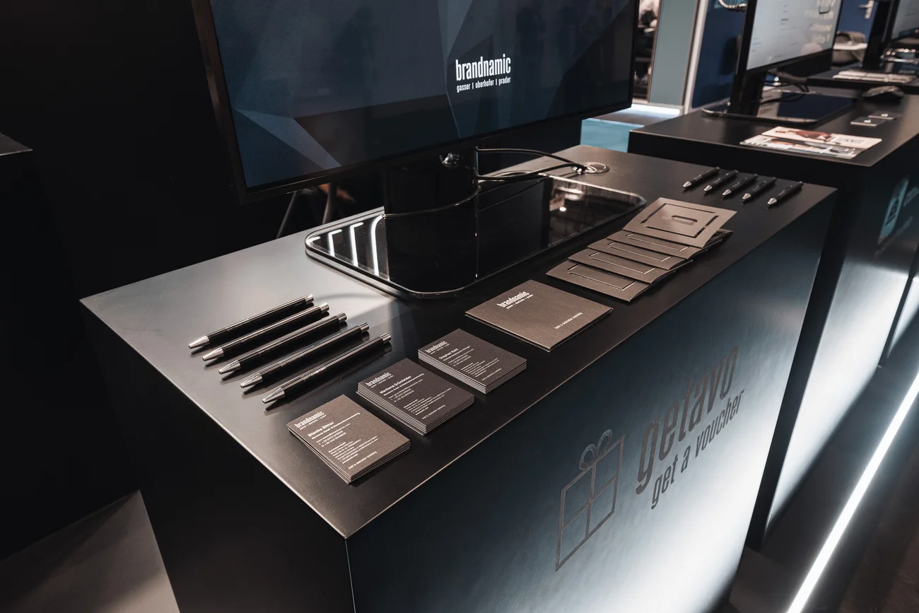 Schwarzer Messestand mit Werbematerialien und Monitor mit Brandnamic-Logo