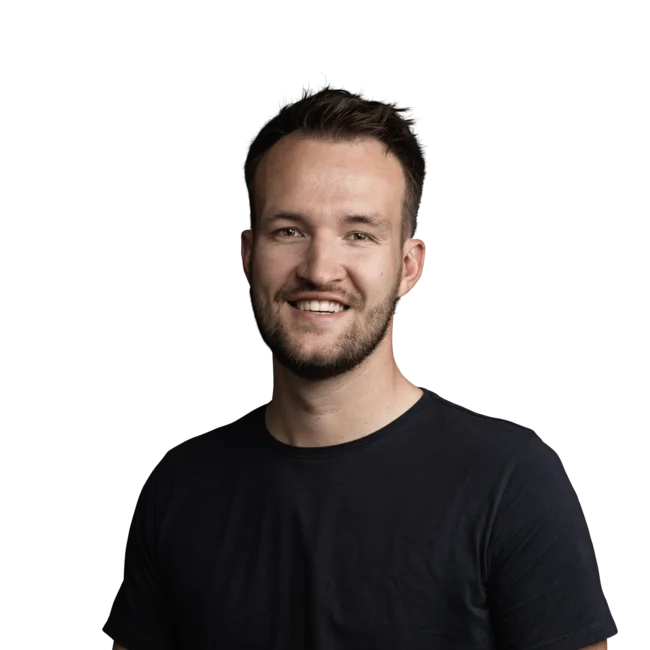 Junger Mann mit dunklem T-Shirt lächelnd vor weißem Hintergrund