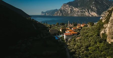 Dorf am Seeufer umgeben von Bergen und grünen Wäldern bei klarem Himmel