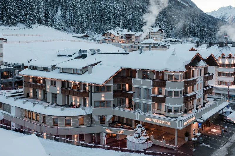 Verschneites Hotelgebäude mit rauchenden Kaminen in Berglandschaft