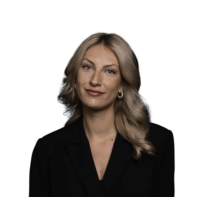 Porträt einer lächelnden Frau mit blonden Haaren und schwarzem Blazer