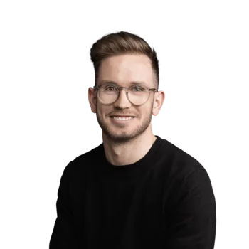 Junger Mann mit Brille und schwarz Pullover lächelt in die Kamera