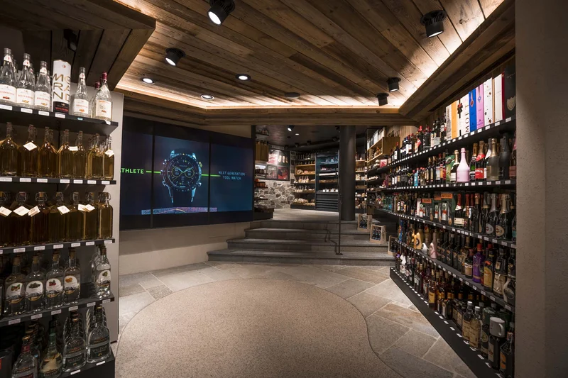 Innenraum eines modernen Spirituosengeschäfts mit Holzdecke und beleuchteten Regalen