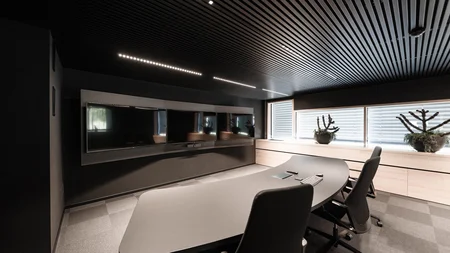 Modern meeting room with large table, chairs, and three screens on the wall