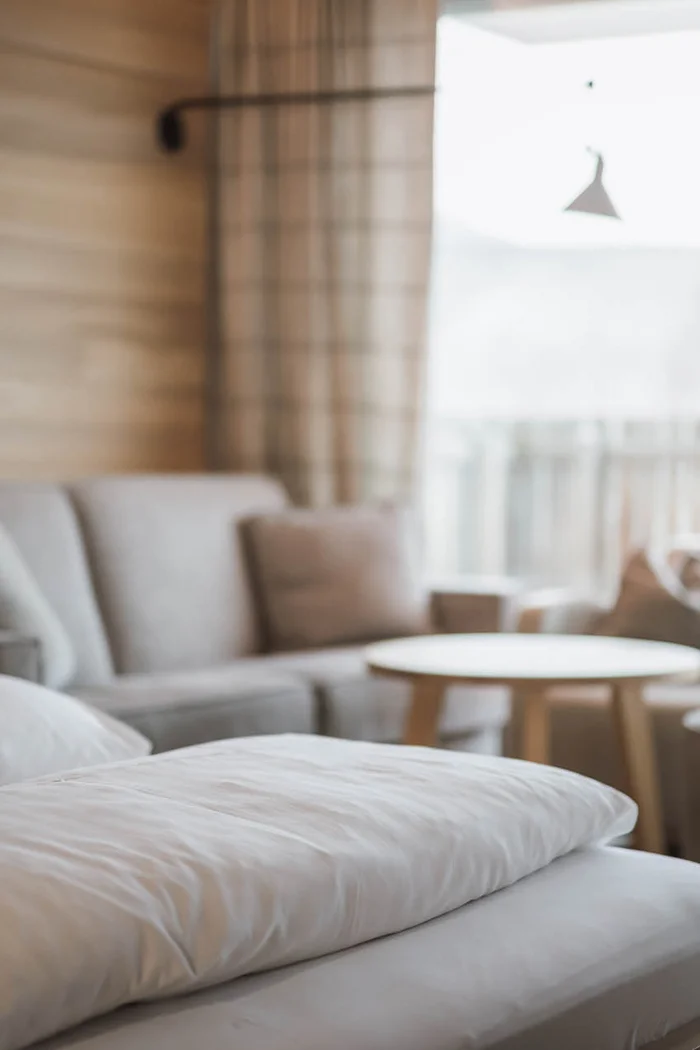 Nahaufnahme weißen Kissens auf Bett in gemütlichem Wohnzimmer mit Sofa und Tisch