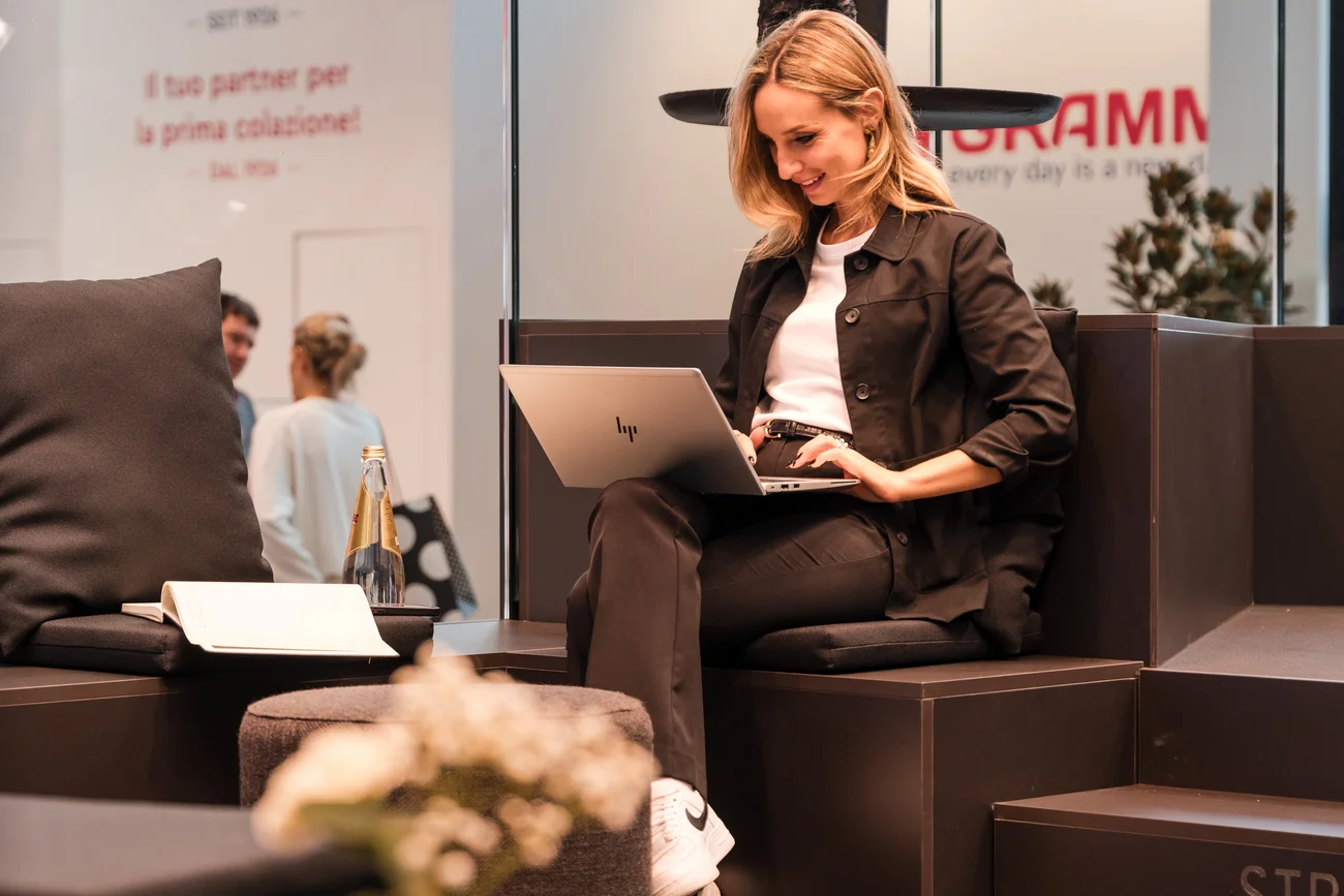 Frau arbeitet mit Laptop in modernem Innenraum mit Sofas und Pflanzen