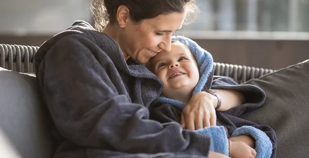 Mother and child warmly embracing on the sofa at home