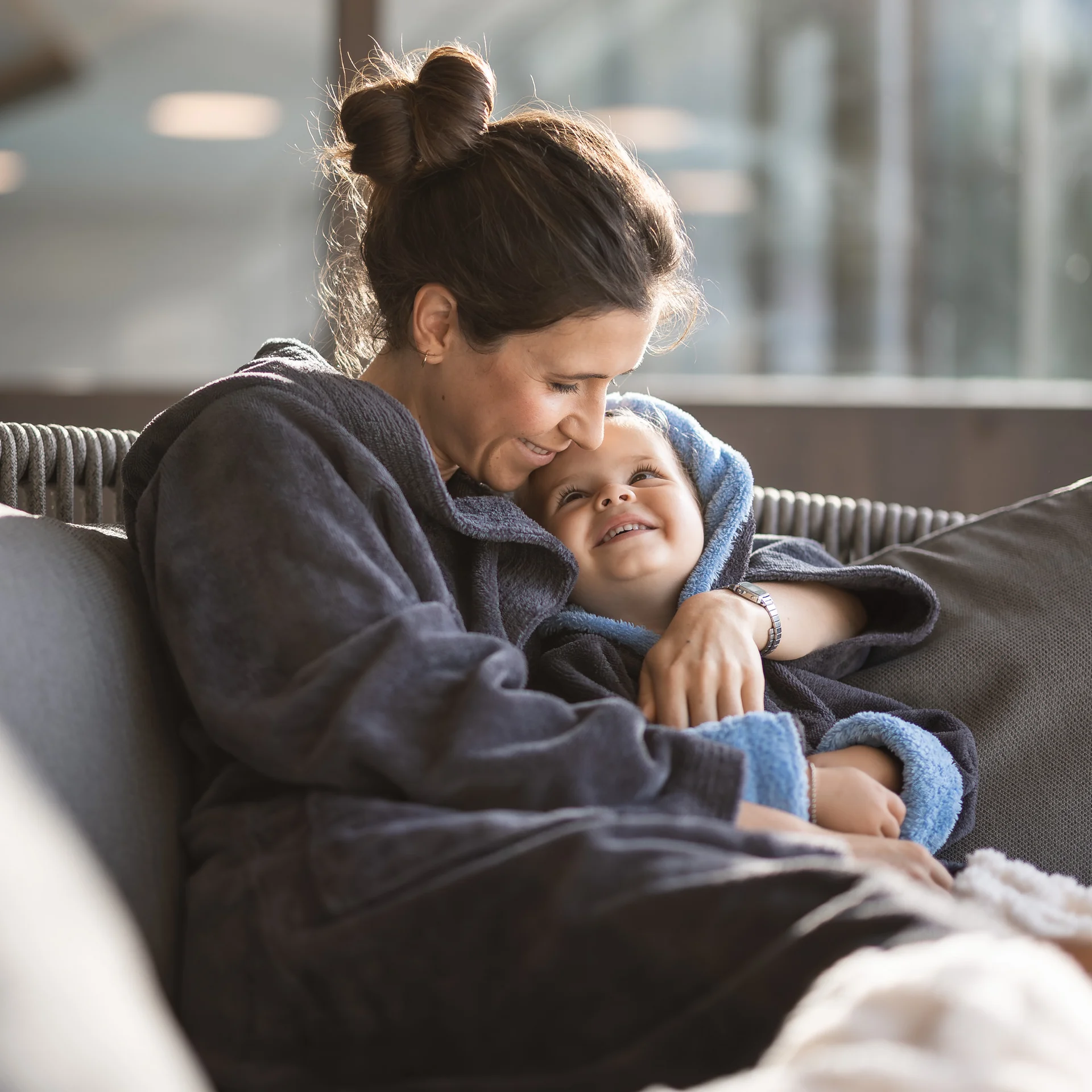 Mother and child warmly embracing on the sofa at home