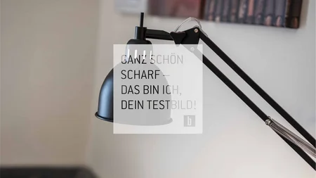 Schwarze Schreibtischlampe an verstellbarem Arm vor heller Wand