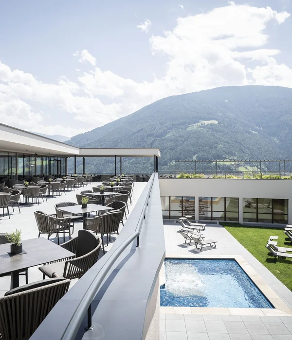 Das Mühlwald: Strategic realignment and sales setup lead to a 50% increase in turnover Modern terrace with tables, pool, and mountain view on a sunny day