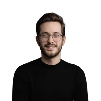 Porträt eines lächelnden jungen Mannes mit Brille und schwarzem Pullover vor weißem Hintergrund
