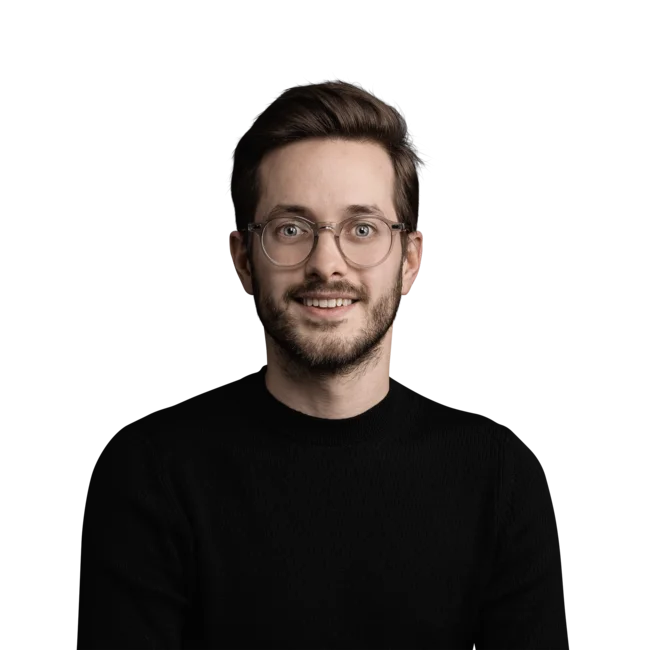 Damiano Ferratello Porträt eines lächelnden jungen Mannes mit Brille und schwarzem Pullover vor weißem Hintergrund