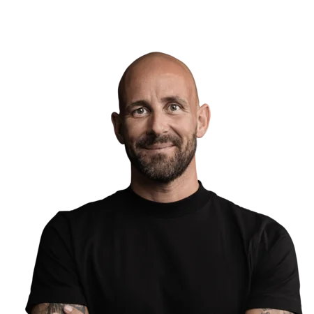 Porträt eines lächelnden, tätowierten Mannes mit schwarzem T-Shirt vor weißem Hintergrund