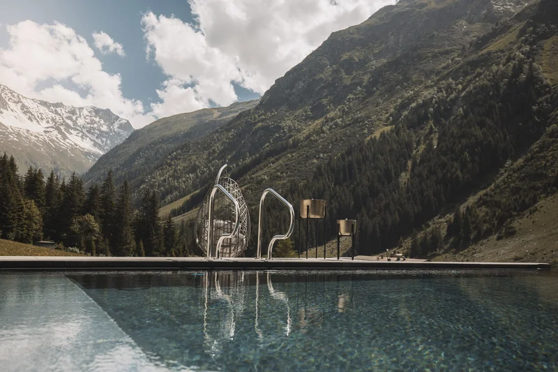 Infinity-Pool in den Bergen mit Metallgeländer und Sitzskulptur