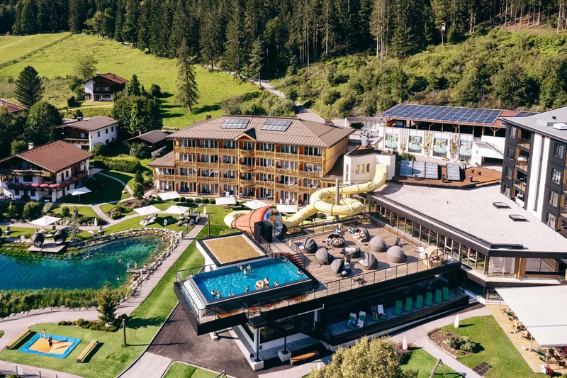 Familienhotel Buchau am Achensee Luftaufnahme eines Hotels mit Pool, Wasserrutsche und umliegender Waldlandschaft