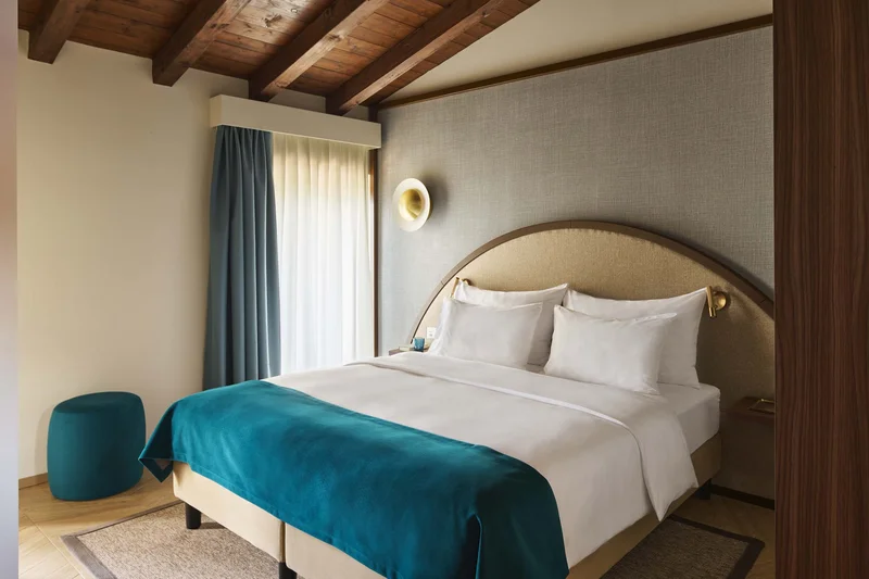 Modernes Schlafzimmer mit Holzbalkendecke und blauem Bettüberwurf