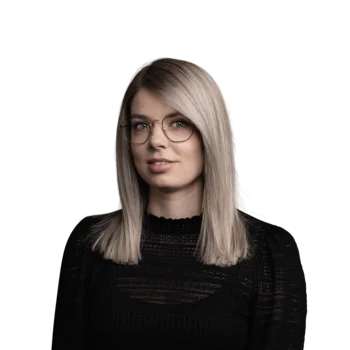 Porträt einer Frau mit Brille und blondem mittellangem Haar in schwarzem Pullover