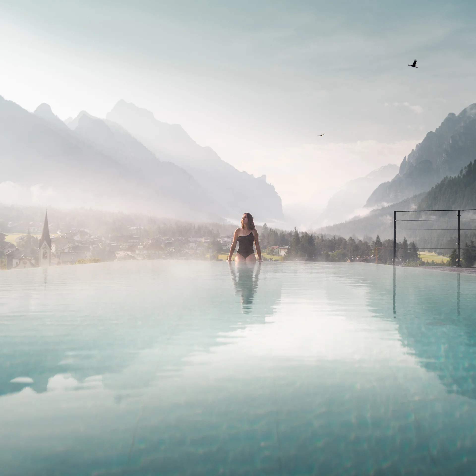 Follow the call of the mountains to St. Vigil Woman in pool with misty mountain landscape in the background