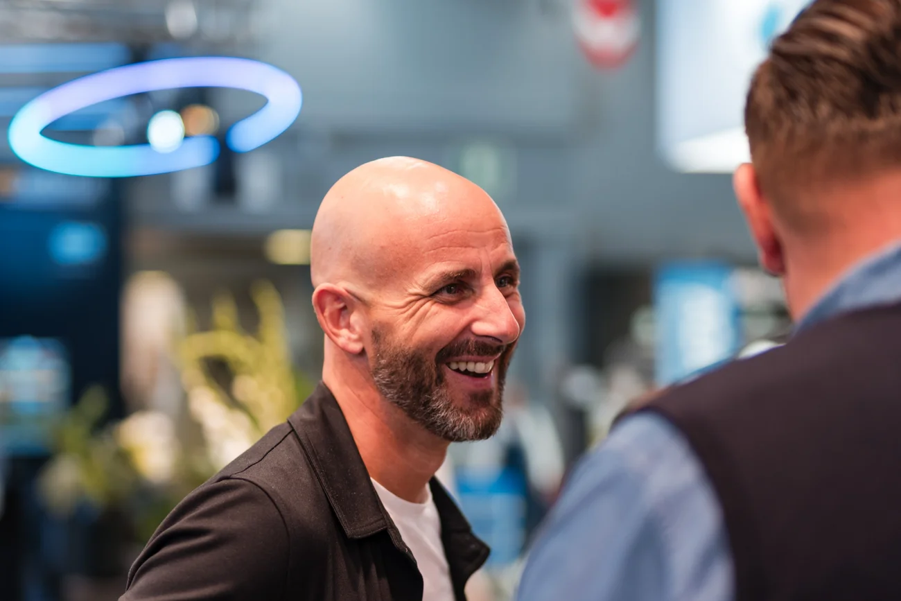 Zwei Männer unterhalten sich lachend in einem modernen, hell beleuchteten Raum