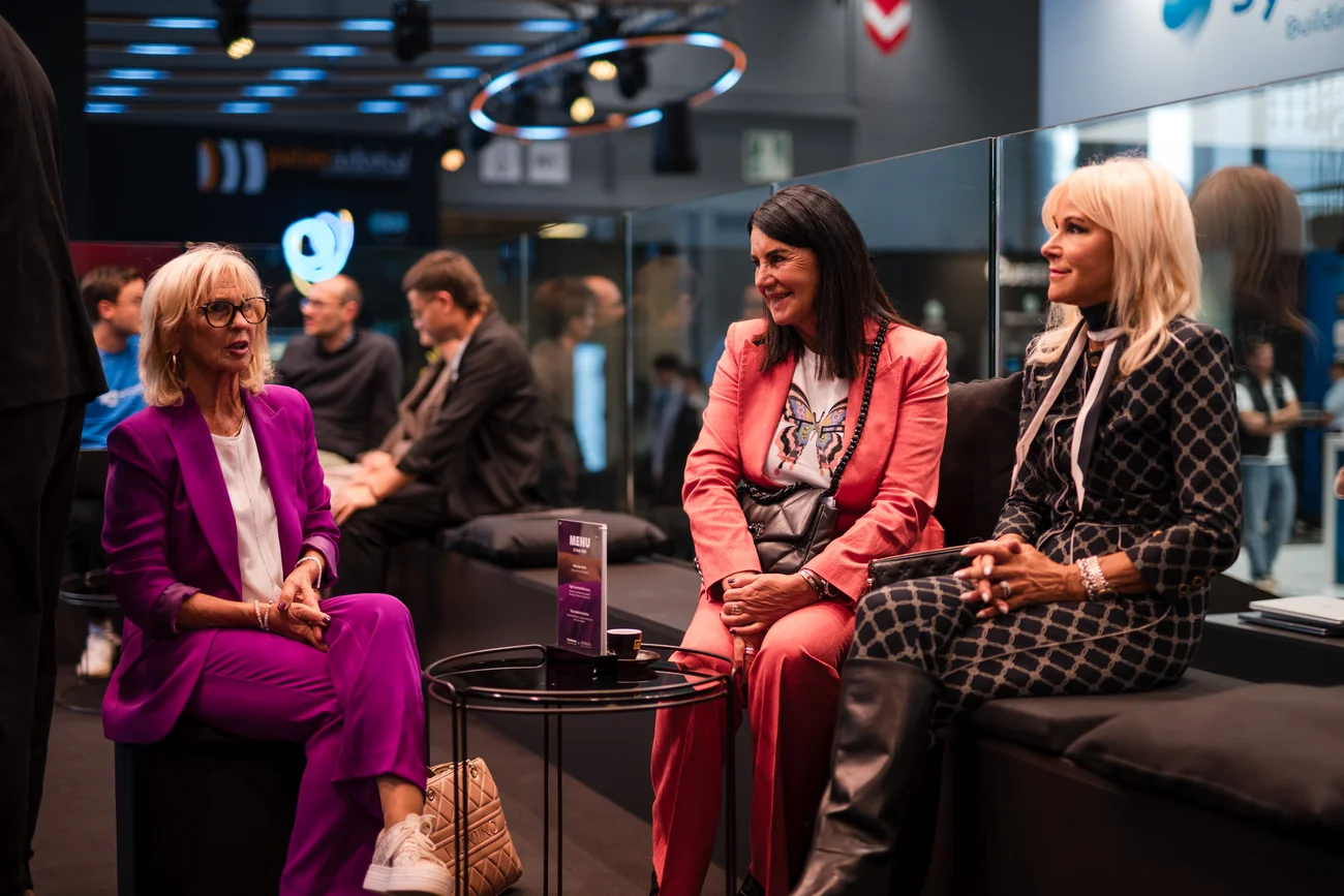 Drei Frauen im Gespräch bei einem Event sitzen auf einer Lounge-Couch