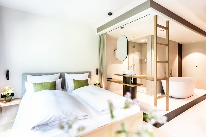 Modernes Hotelzimmer mit Doppelbett und offenem Badezimmer mit Badewanne