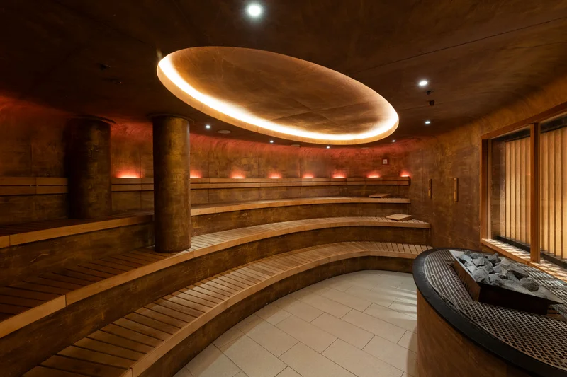 Runde Sauna mit Holzbänken und indirekter Deckenbeleuchtung