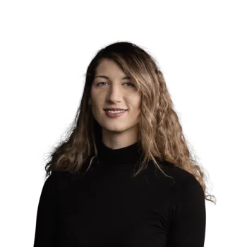 Portrait einer lächelnden Frau mit lockigem Haar und schwarzem Rollkragenpullover