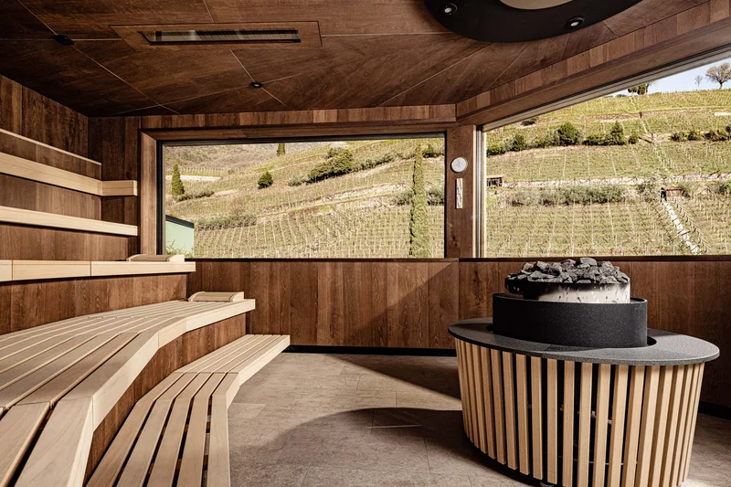 Immerse yourself in Italian dolce vita Wood-paneled sauna room with large windows overlooking hills and vineyards