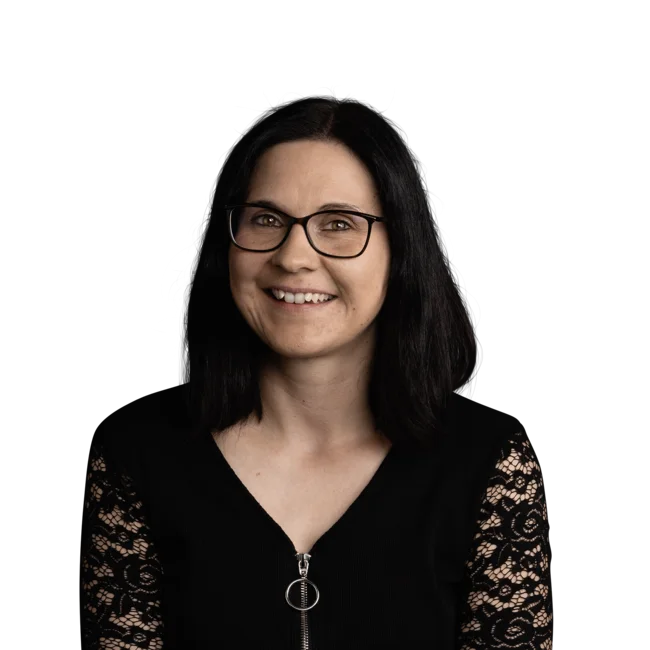 Porträt einer lächelnden Frau mit schwarzen Haaren und Brille vor weißem Hintergrund