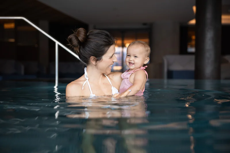 Mother holding smiling baby in indoor swimming pool