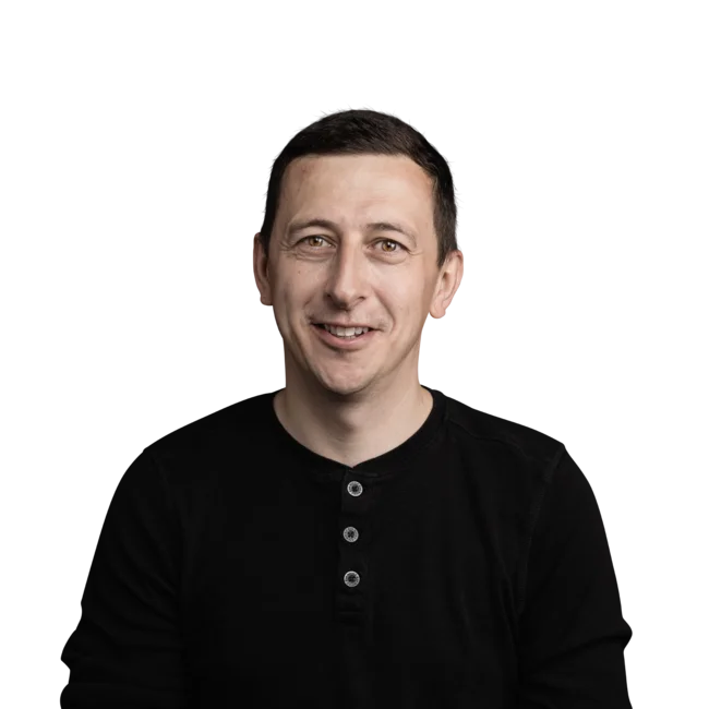 Tobias Lerchegger Ritratto di uomo sorridente con maglia nera a maniche lunghe su sfondo bianco