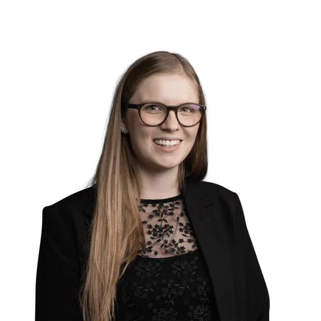Allison Nardon Junge Frau mit langen Haaren, Brille und schwarzem Spitzenoberteil lächelnd