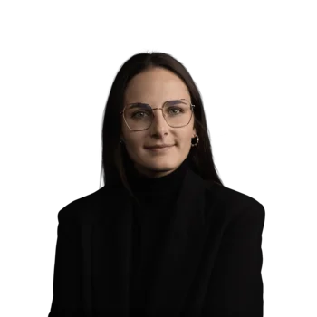 Porträt einer Frau mit schwarzem Blazer und Brille vor weißem Hintergrund