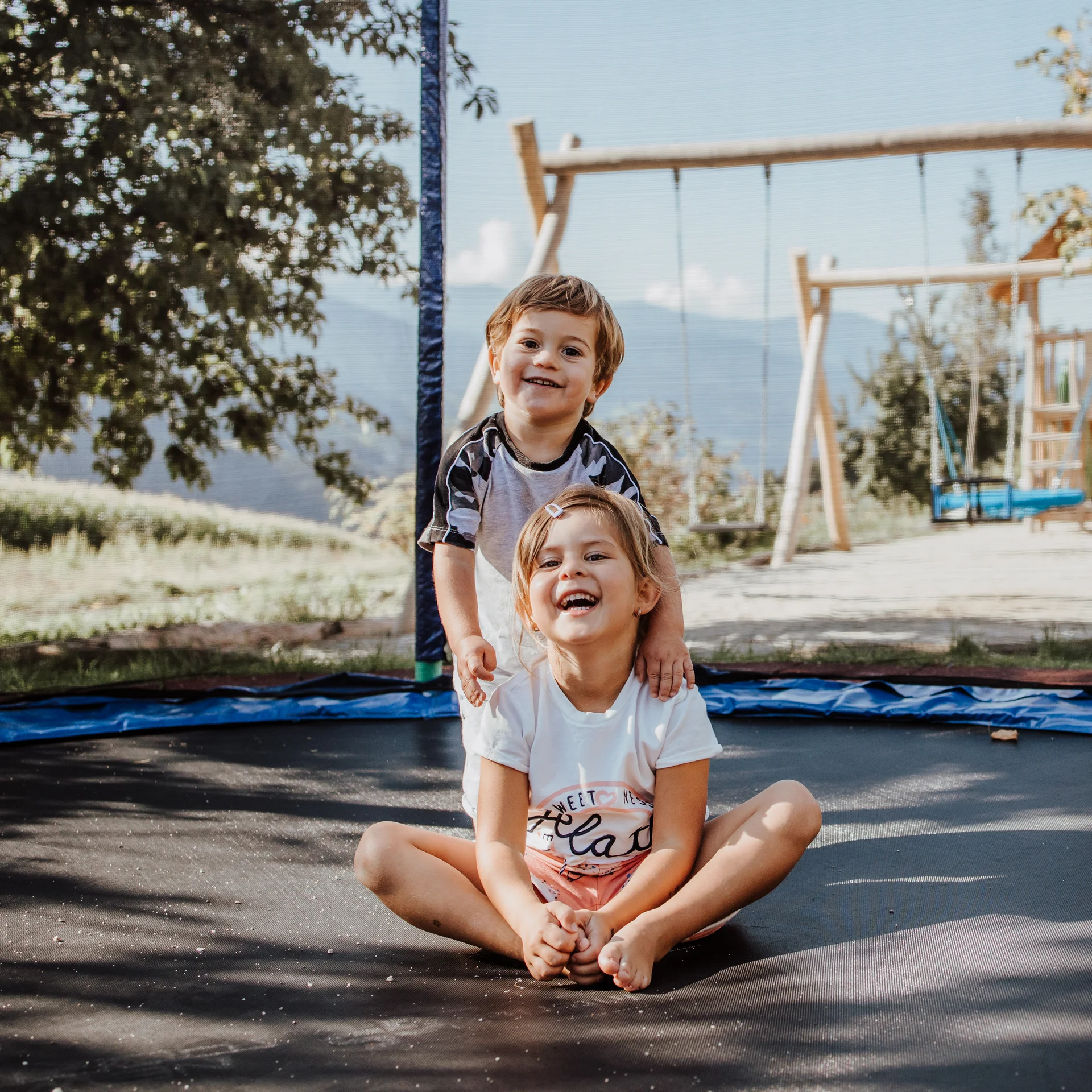 Das Mühlwald: perfectly visible Two happy children playing on an outdoor trampoline on a sunny day