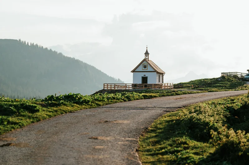 Kleine Kirche am Ende eines gewundenen Wegs in grüner Hügellandschaft