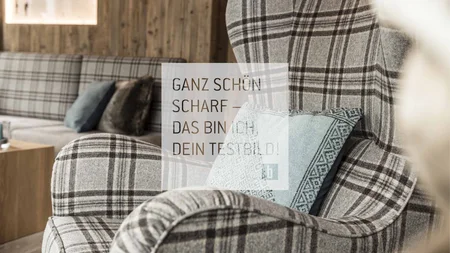 Gepolsterter Sessel mit grauem Karomuster und blauem Kissen im Raum