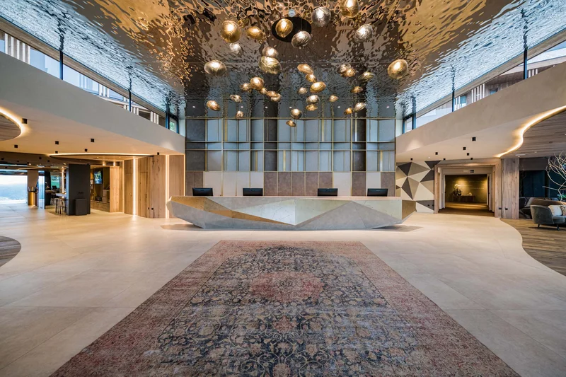 A stylish new website for the Alpen Tesitin in South Tyrol Modern hotel reception with geometric desk and artistic ceiling installation